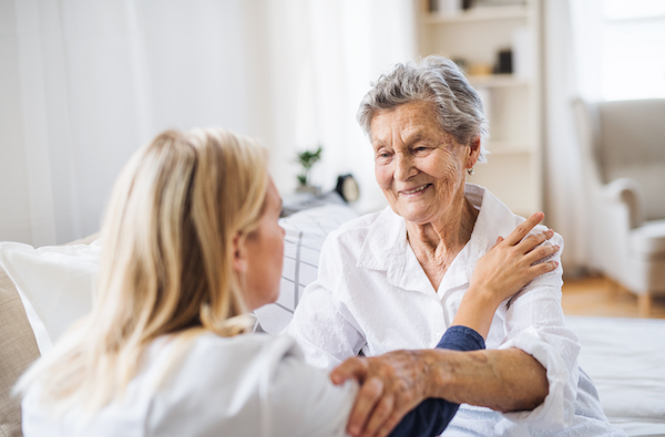a-health-visitor-talking-to-a-sick-senior-woman-sitting-on-bed-at-home-
