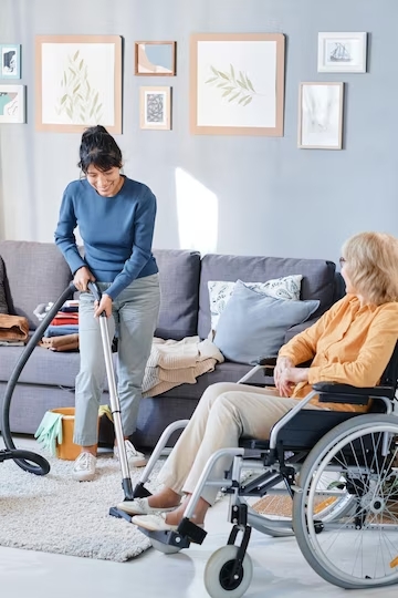 femme-avec-aspirateur-devant-personne-en-fauteuil-roulant