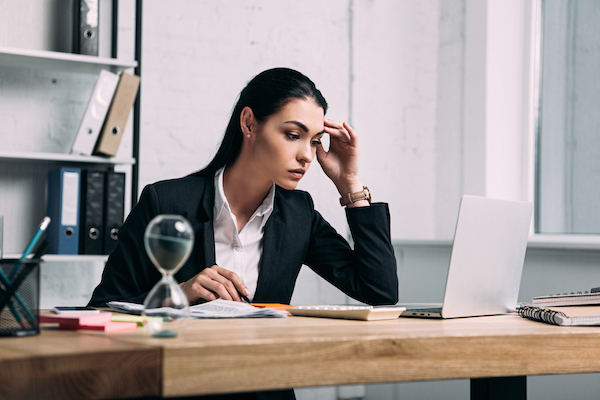 focused-businesswoman-in-suit-working-on-laptop-at-workplace-in-office